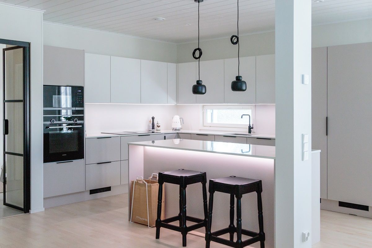 The kitchen is illuminated by full-length LED strip lights in an aluminium profile, ceiling lights suspended above the island, and additional light under the front edge of the island.